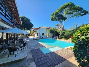 uma piscina com mesas e cadeiras ao lado de um edifício em Pousada Blue Marlin em Búzios