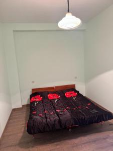 een bed met een zwart dekbed en rode rozen erop bij New Home in Gjoemri