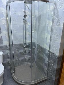 een douche met een glazen deur in de badkamer bij New Home in Gjoemri