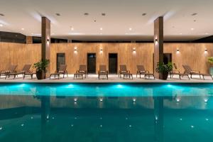 a hotel lobby with a swimming pool and chairs at Vert Hotel Penedo in Penedo