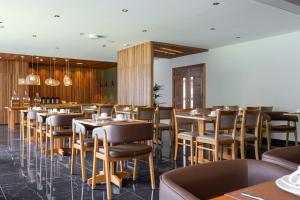 uma sala de jantar com mesas e cadeiras de madeira em Vert Hotel Penedo em Penedo