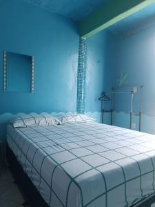 a blue bedroom with a large bed with white sheets at Apartamentos no Farol Velho in Salinópolis