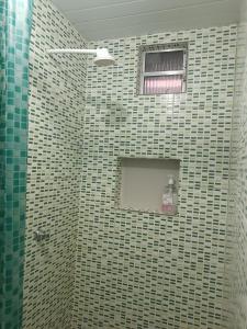 a bathroom with a tiled shower with a window at Apartamentos no Farol Velho in Salinópolis