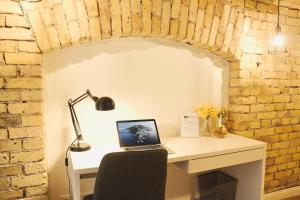 a desk with a laptop computer on top of a brick wall at Tomy Old Town Apartments in Vilnius