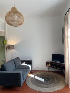 a living room with a blue couch and a television at L'écrin de Mona au coeur de Lourmarin in Lourmarin