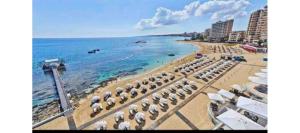 a beach with umbrellas and the ocean with buildings at New studio no2 in the middle off famagusta & NETFLIX in Famagusta