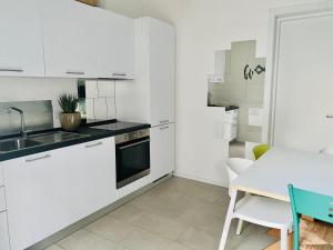 a kitchen with white cabinets and a table and a dining room at Lupicante 56 Cesenatico in Cesenatico