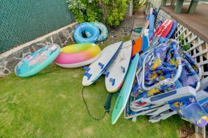 a pile of surfboards andogie boards sitting on the grass at Waianae Beach House with Direct Coast Access and Views in Waianae