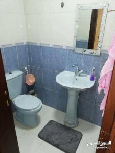 a blue tiled bathroom with a toilet and a sink at شقة مفروشة سكنية في مرج الحمام in Amman