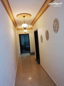 a hallway with a ceiling with a chandelier and a door at شقة مفروشة سكنية في مرج الحمام in Amman