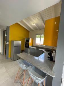 una cucina con pareti gialle e bancone con sgabelli di La buena vida a Pointe-Noire