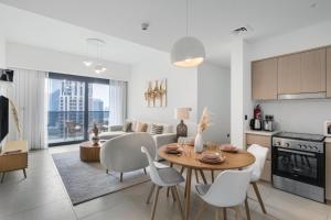 Downtown Dubai- 2BR Apartment in ACT Towers في دبي: مطبخ وغرفة معيشة مع طاولة وكراسي