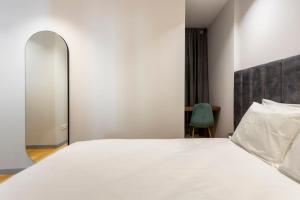 ein Schlafzimmer mit einem großen weißen Bett und einem Spiegel in der Unterkunft Almada 505 City Center Duplex in Porto
