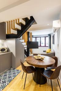 ein Wohnzimmer mit einem Tisch, Stühlen und einer Treppe in der Unterkunft Almada 505 City Center Duplex in Porto
