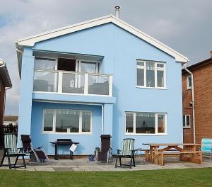 a blue house with a picnic table in front of it at Ann's Beach House in Tywyn in Tywyn