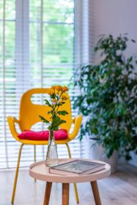 a yellow chair and a table with a vase with flowers at Apartament Bulwary Łyna przy Starym Mieście in Olsztyn