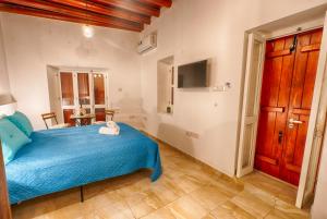 1 dormitorio con 1 cama azul y TV en Penelope's Mansion Omodos en Omodos