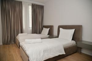2 bedden in een hotelkamer met witte lakens bij Hera Tirana Suite Deluxe in Tirana