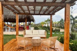 eine Pergola mit einem Sofa und Stühlen auf einer Terrasse in der Unterkunft Brisas de barú in Ararca