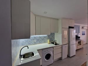a kitchen with white cabinets and a washing machine at Sunset 8F in Santa Pola