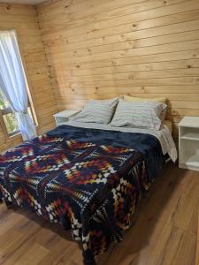 a bedroom with a bed in a wooden cabin at Cabaña Coigües Balneario Punta de Lapas in Quellón