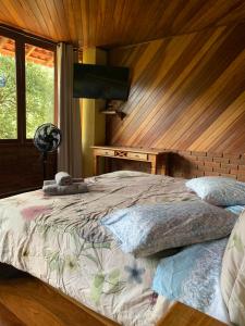 a bedroom with a bed with a wooden wall at Casa Araucária 2 in Visconde De Maua
