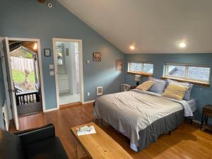 Schlafzimmer mit blauen Wänden, einem Bett und einem Tisch in der Unterkunft Oceanfront Studio/Loft: Alpacas, Oysters & Kayaks in Shelton