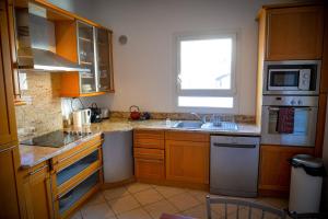 uma cozinha com armários de madeira, um lavatório e uma janela em Rosella - Terrasse rooftop, hypercentre, wifi - by TGB em Ajaccio