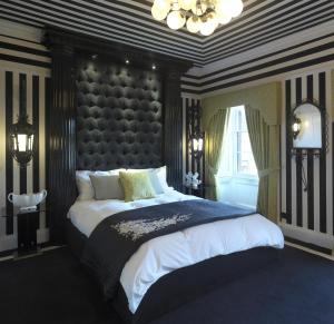 a bedroom with a large bed with a large headboard at Carrington House in Snettisham