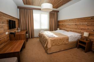 1 dormitorio con 1 cama y pared de madera en Šport Hotel *** Donovaly en Donovaly
