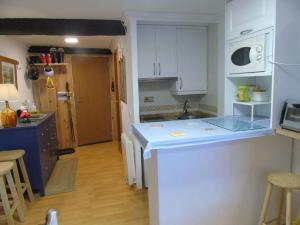 uma cozinha com armários brancos e um balcão azul em Acogedor apartamento de montaña em Sierra Nevada