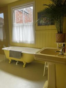 a yellow bathroom with a tub and a window at Hastings Old Town Gorgeousness in Hastings