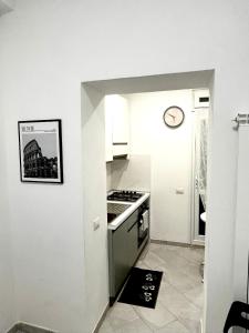 une petite cuisine avec une cuisinière et une horloge murale dans l'établissement ROMA LUXURY House Colosseo, à Rome