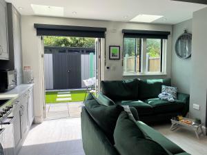 uma sala de estar com um sofá verde e uma cozinha em Superb townhouse near vibrant Gloucester Road em Bristol