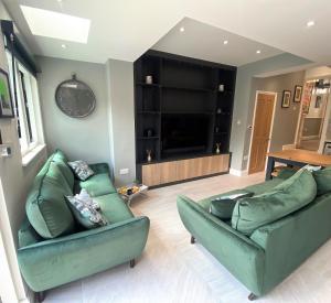 a living room with two green couches and a television at Superb townhouse near vibrant Gloucester Road in Bristol