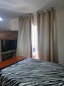 um quarto com uma cama e uma janela com uma televisão em Suíte Temporada Verão em Torres