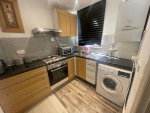 a kitchen with a stove and a washer and dryer at the woods 2 in London