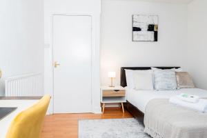 Cozy 1-Bedroom Flat at Abingdon في أوكسفورد: غرفة نوم بيضاء مع سرير وطاولة