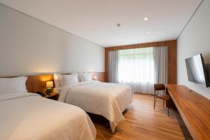 a hotel room with two beds and a window at Vert Hotel Penedo in Penedo