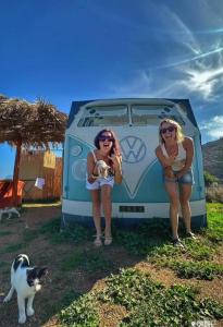 zwei Frauen stehen vor einem Wohnwagen mit einer Katze in der Unterkunft Magic Bus in Kissamos