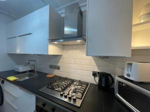 a kitchen with a stove top oven next to a sink at Central Point apartment in London