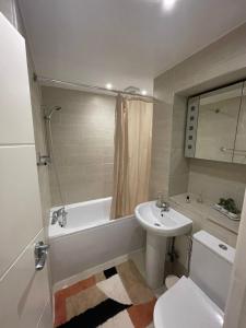 a bathroom with a sink and a tub and a toilet at Central Point apartment in London