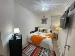 Dormitorio pequeño con cama con manta naranja en Central Point apartment en Londres