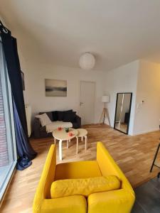 a living room with a yellow couch and a table at Appartement neuf avec balcon/ fibre/parking privé in Massy