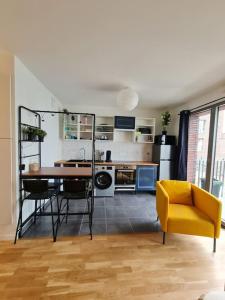 a living room with a table and a yellow chair at Appartement neuf avec balcon/ fibre/parking privé in Massy