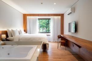 um quarto com uma cama e uma banheira em Vert Hotel Penedo em Penedo