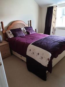 una camera da letto con un letto con lenzuola viola e una finestra di The Annexe a Bridlington