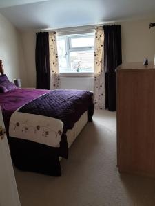 a bedroom with a purple bed and a window at The Annexe in Bridlington
