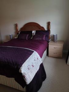 a bedroom with a bed with purple sheets and a night stand at The Annexe in Bridlington