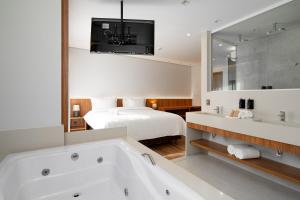 a bathroom with a bath tub and a bed at Vert Hotel Penedo in Penedo